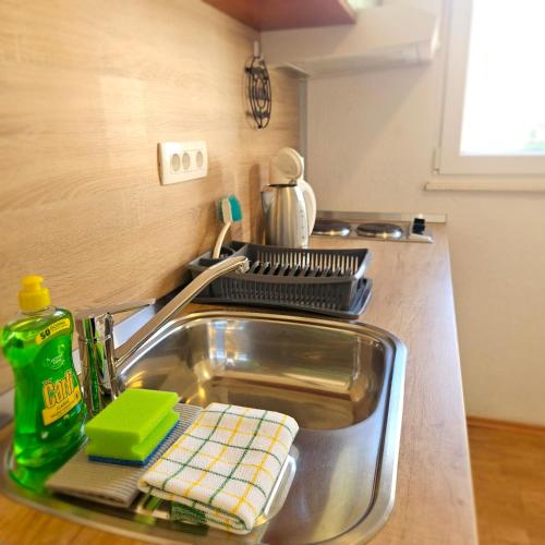 a kitchen sink with a green dish drying rack on it at Apartment Viniška in Vinišće