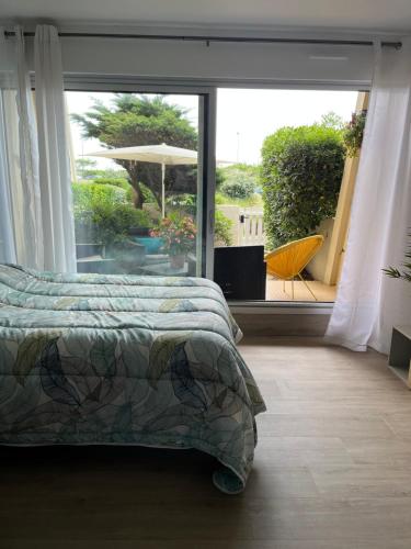 une chambre avec un lit et une grande fenêtre en verre dans l'établissement Studio cosy à 1mn de la mer, jardin et parking privé, à Saint-Jean-de-Monts