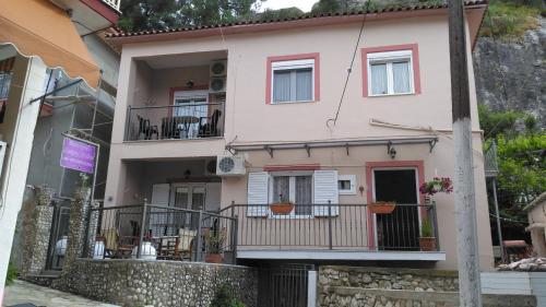a pink house with balconies on a street at Paraskevi's Luxury Studios in Parga