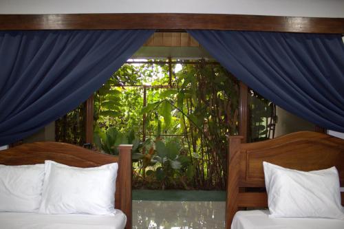 a bedroom with two beds and a window with blue curtains at Home La Fortuna in Fortuna