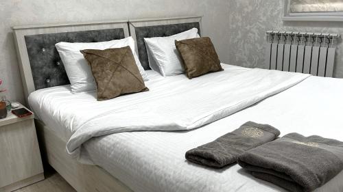 Un dormitorio con una cama grande con sábanas y almohadas blancas. en The Apartment, en Tashkent