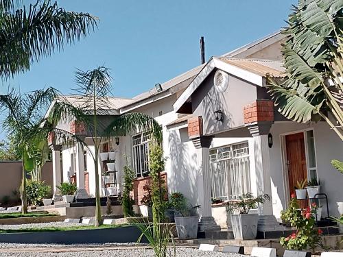 a white house with palm trees in front of it at Warm Care Executive Apartments in Mpemba