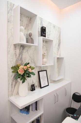 a white shelf with a vase of flowers on it at Sol Hotel in Shkodër