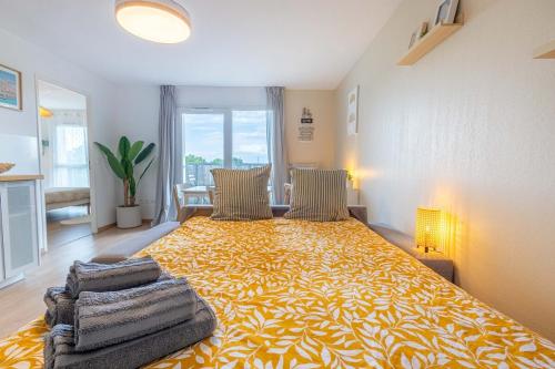 une chambre avec un grand lit avec une couverture jaune dans l'établissement Bright apartment with terrace and parking, à Mérignac