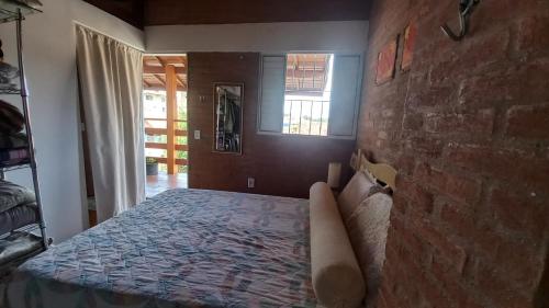a bed in a room with a brick wall at CASA DO BRAZ aptos e casa de temporada in Monte Verde