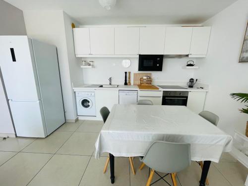 une cuisine blanche avec une table et un réfrigérateur dans l'établissement Charmant 2 pièces proche Croisette, à Cannes