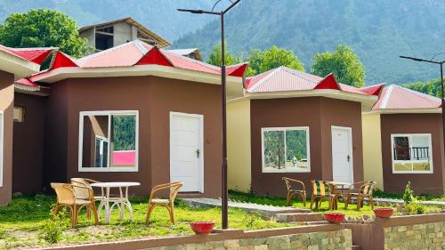 a row of houses with chairs and a table at Florid Hotel and Resort Kalam in Kalām