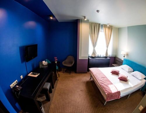 a blue room with a bed and a desk and a television at Hotel Arena in Târgu-Mureş