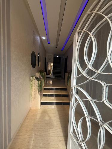 a hallway with a door and stairs with blue lights at Comfortable and quiet apartment with Buzzinga in Bouznika