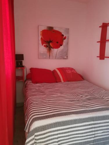 - une chambre avec un lit orné d'un tableau de fleurs rouges sur le mur dans l'établissement Ajaccio VUE MER IMPRENABLE 4a5 Pers, à Ajaccio