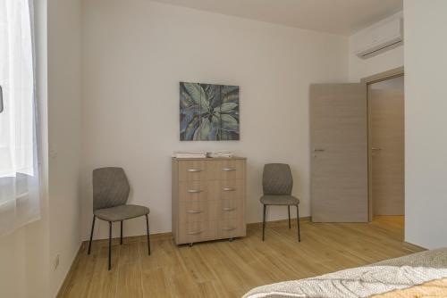 a bedroom with two chairs and a dresser with a painting at LOANO PERLA LIGURE in Loano