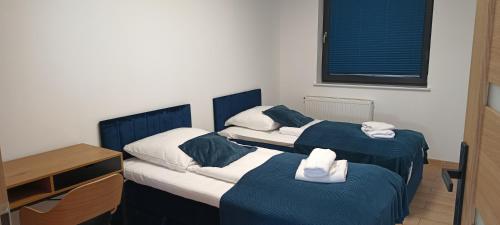 two twin beds in a room with a desk and a desk at Apartament Luna in Gryfice