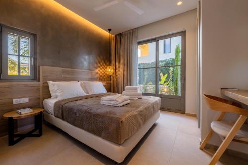 a bedroom with a bed and a desk and windows at Casa Tierra - Villa I in Kos Town