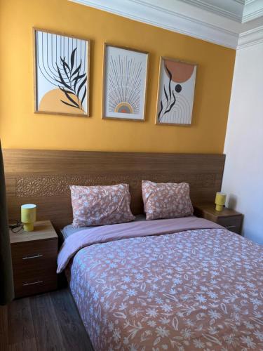 a bedroom with a bed with three pictures on the wall at Julie's AIRPORT Apartment in Marrakech