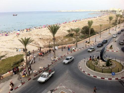 a street in front of a beach with cars and people at Ariane Appartment - Residence Espadon in Mahdia