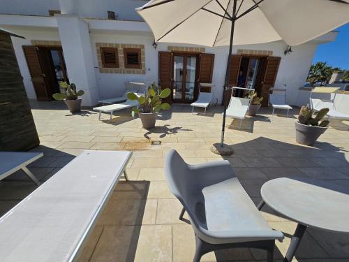 a patio with tables and chairs and an umbrella at Lido Marini Rooms Affittacamere B&B in Lido Marini
