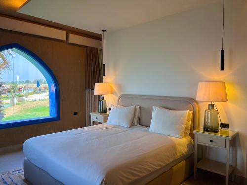 a bedroom with a white bed with a window at venecia Resort Fayoum in Al Ḩammām