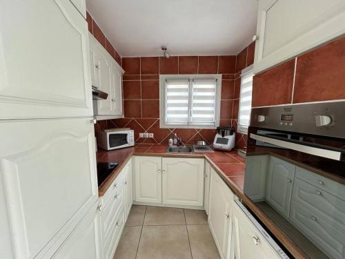 une cuisine avec des placards blancs et du carrelage rouge dans l'établissement Desbo, à Valras-Plage