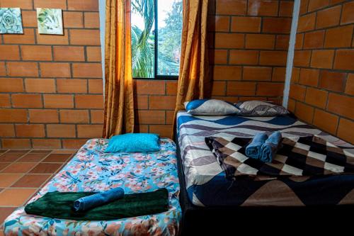 two beds sitting next to a brick wall at Habitación para 4 con acceso al rio baño privado y wifi San Rafael Antioquia in San Rafael