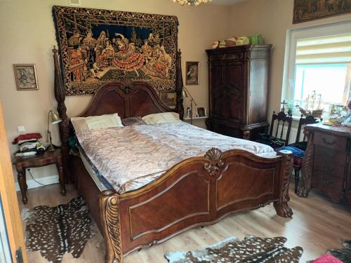 a bedroom with a large wooden bed with a painting on the wall at Roberto ranch in Palanga