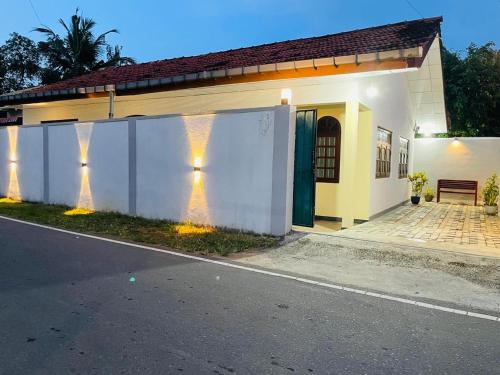 a white house with lights on the side of it at Dream Villa Homestay Madiha in Matara