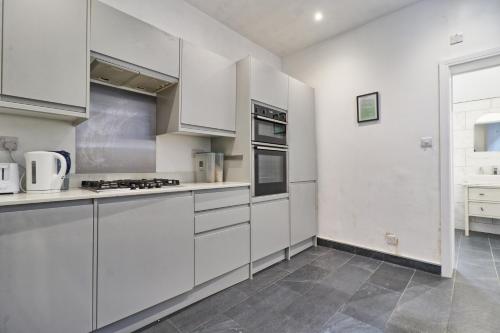 a white kitchen with white cabinets and appliances at Ivy on Sea Villa in Southend-on-Sea