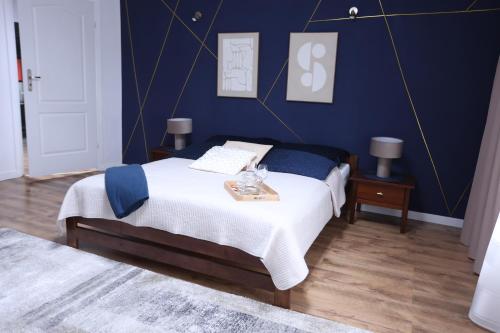 a bedroom with a bed with a blue wall at The Castle Terrace Apartment 100m2 in Ciechanów