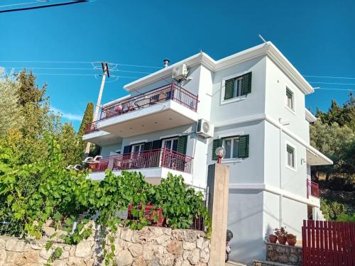 a white house with red balconies and vines at Monika Lefkada in Tsoukaladhes