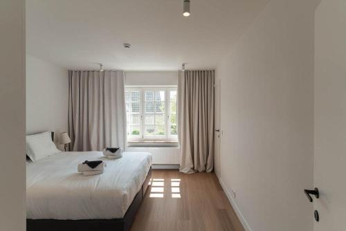 a white bedroom with a bed and a window at Villa 'La Mer Veille - Bécassine' in Oostduinkerke - Bad in Oostduinkerke