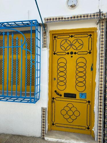 a yellow door on a white wall with a blue gate at Des appartements a la Marsa plage Pieds dans l'eau in Dar Salah Bey