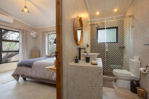 a bedroom with a bed and a toilet and a shower at Chui House A Bush Retreat with Pool and AC Near Kruger Gate in Marloth Park