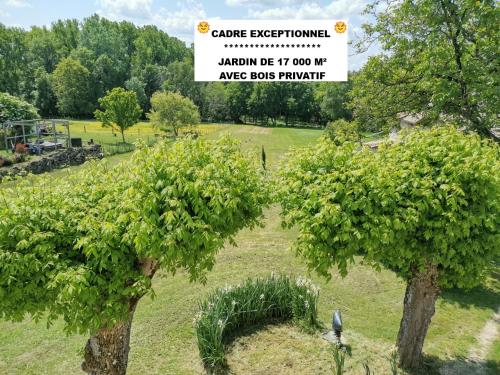 deux arbres dans un champ avec un panneau dans l'établissement Maison avec grand jardin & bois privé en Dordogne, à Minzac