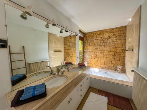 une salle de bain avec un lavabo et un grand miroir dans l'établissement Les champs d'Hermier avec Piscine, à Carsac-Aillac