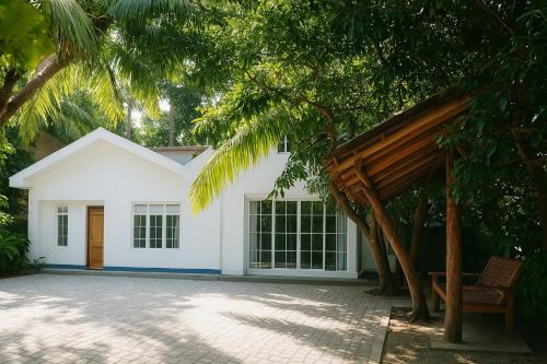 una casa bianca con una porta in legno e alberi di The Beach House , Nilaveli , Trincomalee a Trincomalee