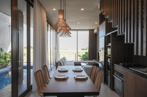 a dining room with a table and chairs and a pool at Cozy 2BR Villa at Kedungu in Tabanan