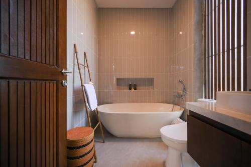 a bathroom with a tub and a toilet and a sink at Cozy 2BR Villa at Kedungu in Tabanan