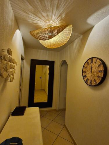 a hallway with a clock on the wall and a mirror at Nidu Di Lume, Charmant T3, 2 chambres, vue mer in Algajola