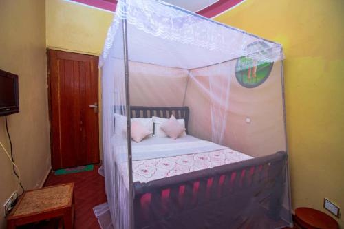 a small bed with a canopy in a room at Pacific Cottages and Guest House Jinja in Jinja