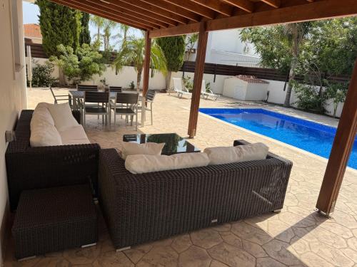 a patio with two couches and a table and a pool at Sunset Villa Agia Thekla in Ayia Napa