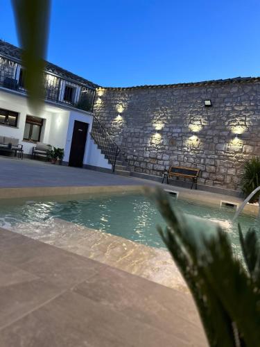 a swimming pool in front of a stone building at El Rincón de la Villa in Sabiote