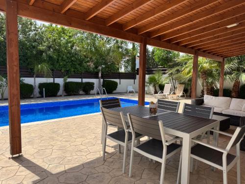 a patio with a table and chairs and a pool at Sunset Villa Agia Thekla in Ayia Napa
