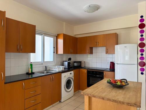 a kitchen with wooden cabinets and a white refrigerator at Sunset Villa Agia Thekla in Ayia Napa