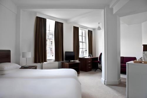 a white hotel room with a bed and a desk at Goodenough College – University Residence in London