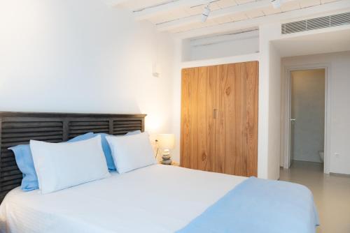 a bedroom with a white bed and a wooden door at The Summit of Mykonos in Kalo Livadi