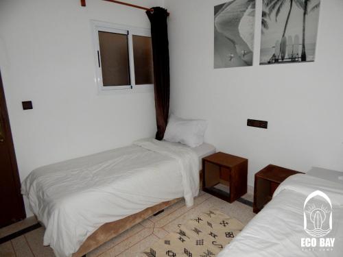 two beds in a room with white walls at Eco Bay Surf Camp in Aourir
