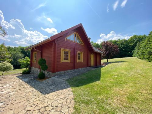 a small red house on a grass field at Parádsasvári Sasfészek in Parád