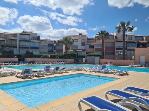 une piscine avec des chaises longues et des chaises tout autour dans l'établissement Appt Studio cabine CAP D'AGDE CT340-314, au Cap d'Agde