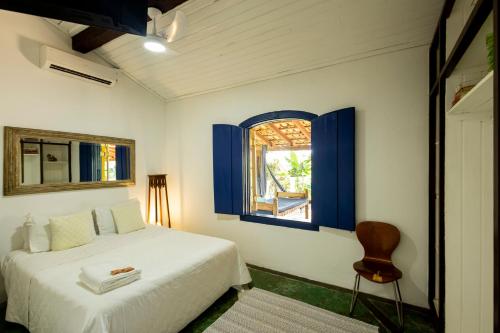 a bedroom with a bed and a window and a chair at Ilhabela Homestay in Ilhabela
