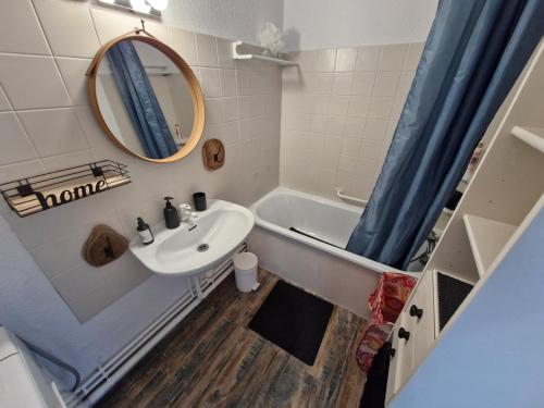 une salle de bain avec un lavabo, une baignoire et un miroir dans l'établissement Le Lagon Bleu - Piscine, à Fréjus