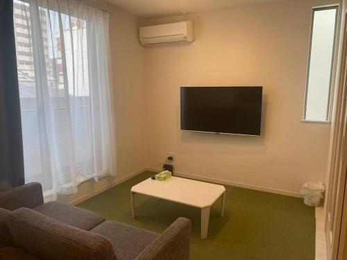 a living room with a couch and a tv on the wall at Camper in Kumamoto